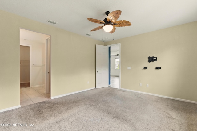 empty room with a ceiling fan, visible vents, attic access, carpet flooring, and baseboards