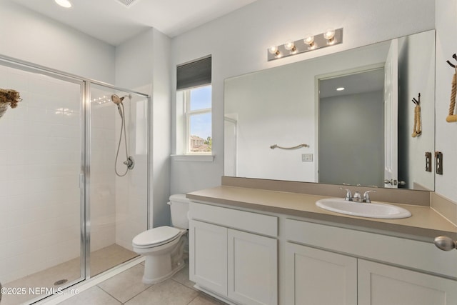 bathroom with a shower stall, vanity, tile patterned flooring, and toilet