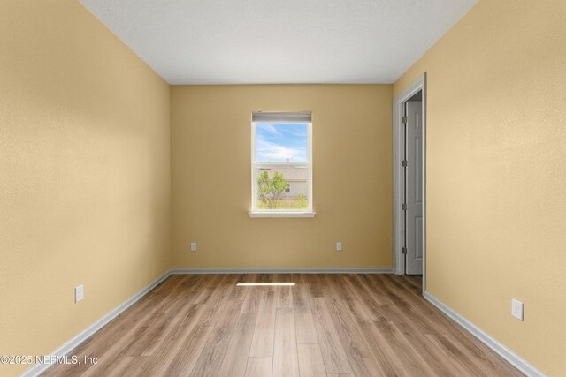 empty room featuring wood finished floors and baseboards