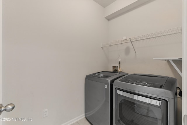 laundry area with washer and clothes dryer, light tile patterned floors, laundry area, and baseboards