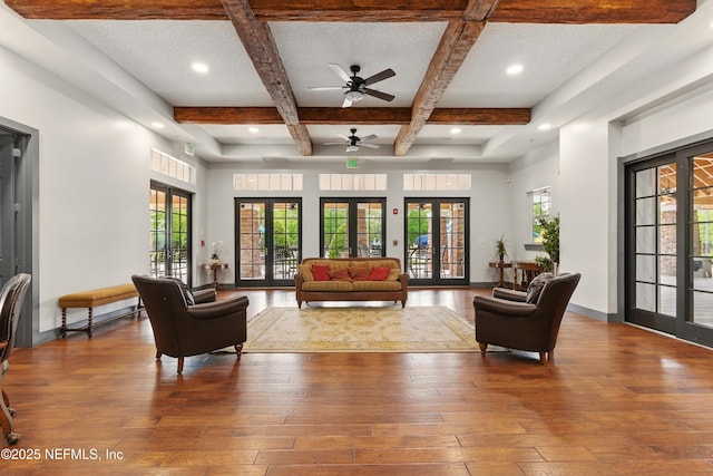 living area with a textured ceiling, a ceiling fan, beamed ceiling, hardwood / wood-style floors, and coffered ceiling