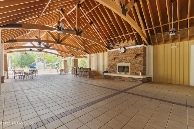 view of patio featuring outdoor dining space, ceiling fan, a gazebo, and an outdoor stone fireplace