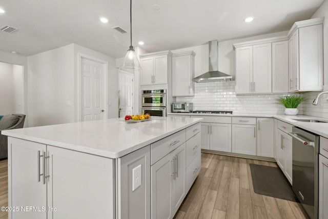 83 Woodgate Dr, Ponte Vedra, FL 32081 - kitchen featuring light wood-style flooring, wall chimney range hood, a center island, appliances with stainless steel finishes, and a sink
