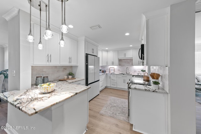 1018 14th Ave N, Jacksonville Beach, FL 32250 - kitchen with a peninsula, freestanding refrigerator, and white cabinets