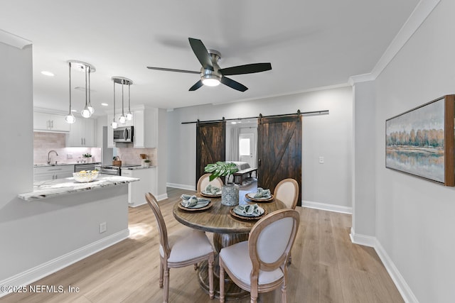 1018 14th Ave N, Jacksonville Beach, FL 32250 - dining room with light wood-style floors, ceiling fan, baseboards, and a barn door