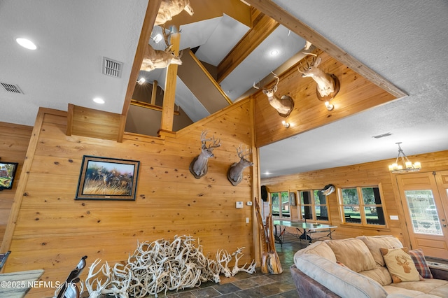 living area with stone finish floor, wooden walls, and visible vents
