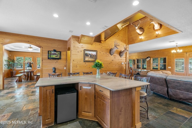 kitchen with wood walls, a wealth of natural light, fridge, and stone tile floors