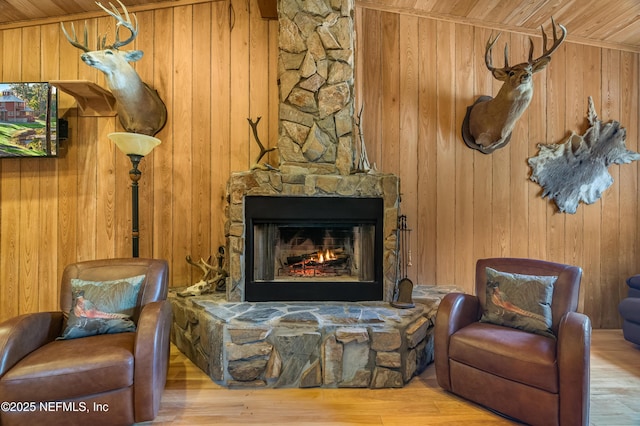 sitting room featuring wood walls, a stone fireplace, and wood ceiling