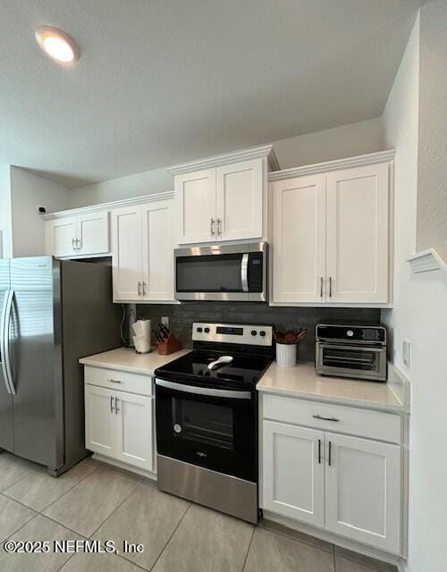 kitchen featuring light countertops, white cabinetry, appliances with stainless steel finishes, and tasteful backsplash