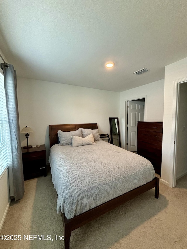bedroom with light carpet, visible vents, and baseboards