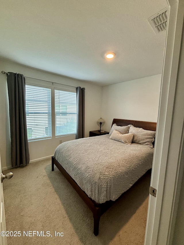 bedroom with baseboards, visible vents, and carpet