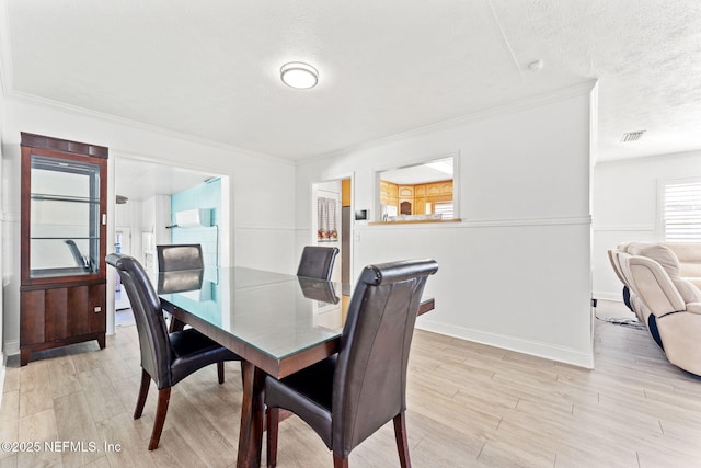 8871 Manson Cir, Jacksonville, FL 32220 - dining area featuring light wood-style flooring, a textured ceiling, and crown molding