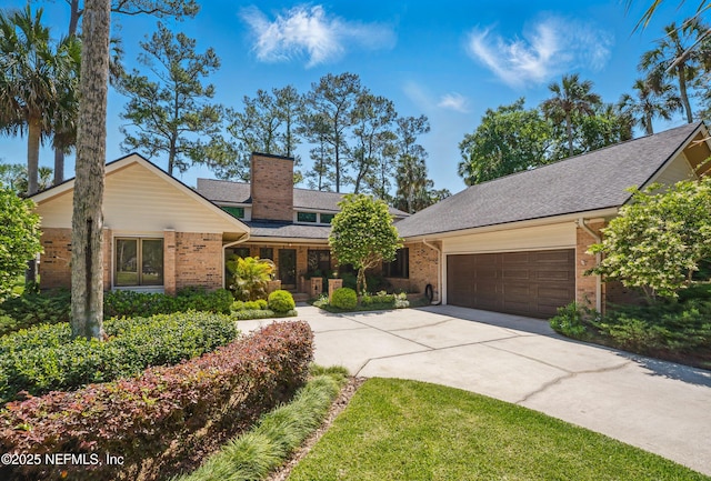 view of front facade featuring brick siding, concrete driveway, an attached garage, a chimney, and roof with shingles