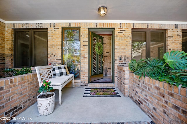 entrance to property with a porch and brick siding