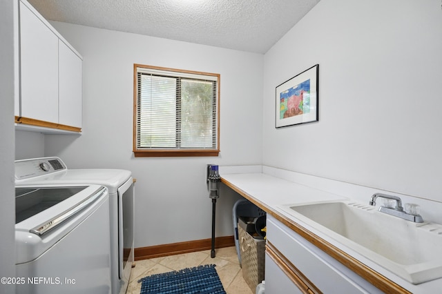 clothes washing area with cabinet space, washing machine and clothes dryer, a textured ceiling, baseboards, and light tile patterned floors