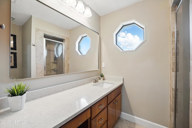 full bathroom with a stall shower, baseboards, vanity, and tile patterned flooring