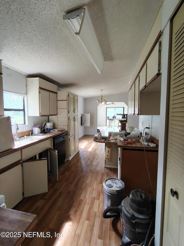 kitchen featuring an inviting chandelier, black dishwasher, a sink, a textured ceiling, and wood finished floors