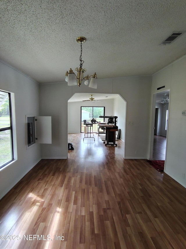unfurnished dining area with visible vents, arched walkways, a notable chandelier, a textured ceiling, and wood finished floors