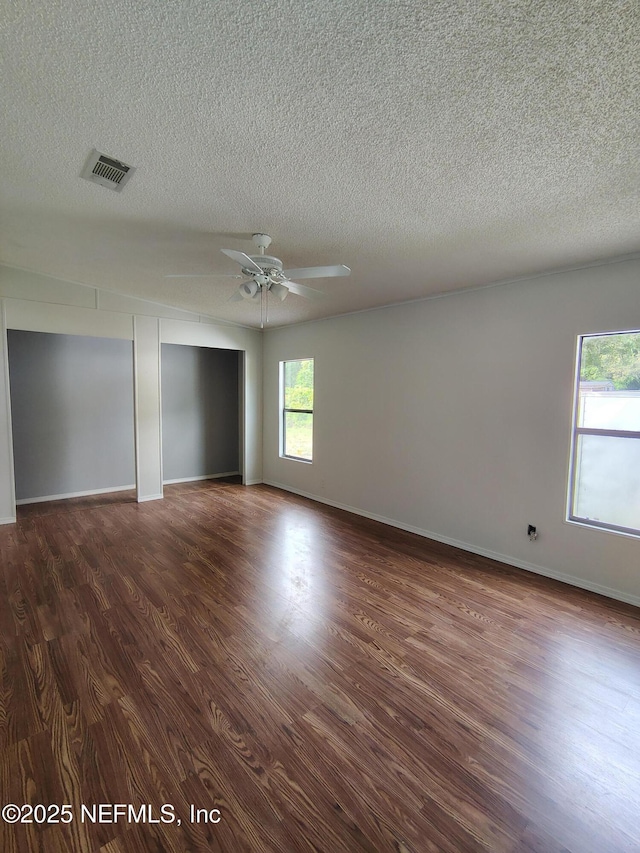 unfurnished room featuring a ceiling fan, a textured ceiling, dark wood finished floors, and visible vents