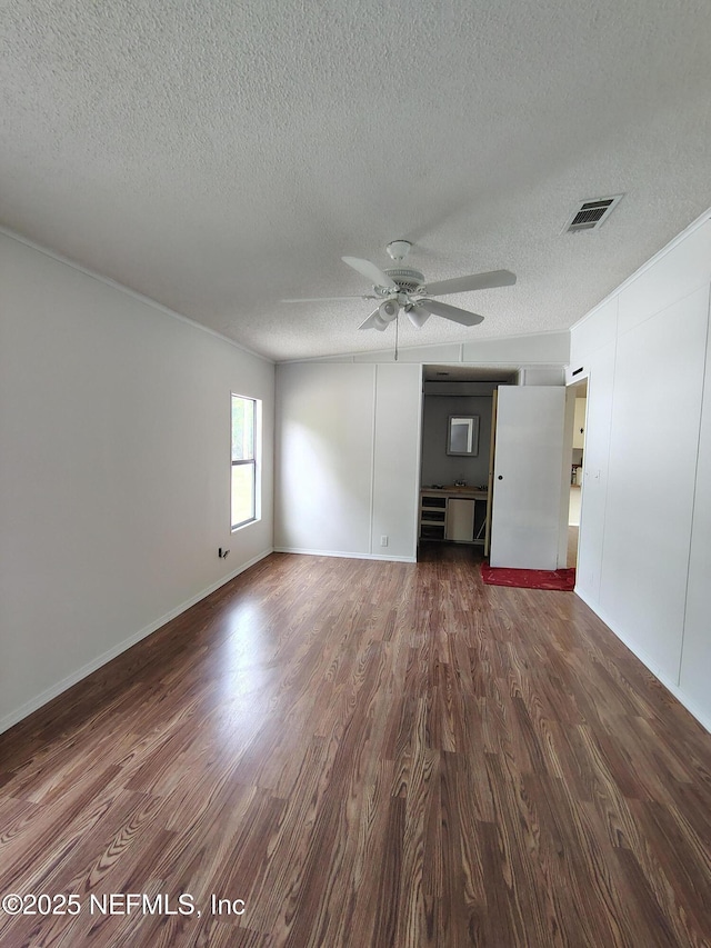 spare room with dark wood-style flooring, visible vents, a ceiling fan, and a textured ceiling
