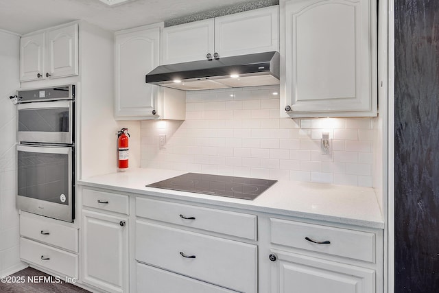 9 Blare Dr, Palm Coast, FL 32137 - kitchen with white cabinetry, black electric cooktop, under cabinet range hood, stainless steel double oven, and decorative backsplash