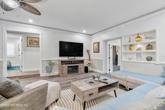 9 Blare Dr, Palm Coast, FL 32137 - living room featuring ornamental molding, a ceiling fan, a glass covered fireplace, wood finished floors, and baseboards