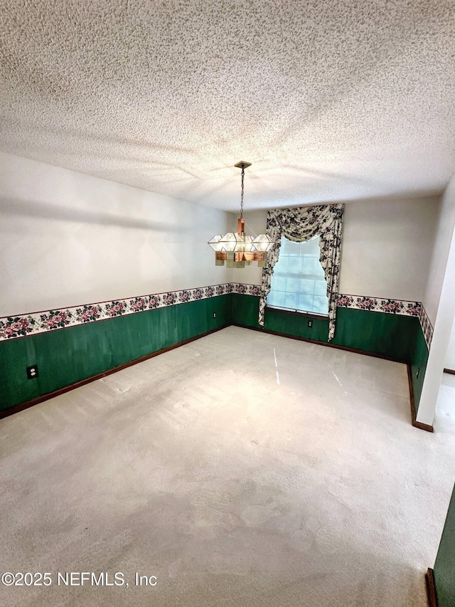 unfurnished dining area with a wainscoted wall, an inviting chandelier, and carpet
