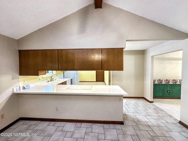 kitchen featuring a peninsula, light countertops, vaulted ceiling, and baseboards