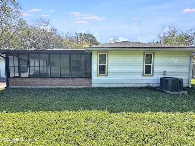 back of property featuring brick siding, central AC unit, a sunroom, and a lawn