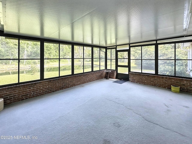 unfurnished sunroom with a wealth of natural light, carpet floors, and brick wall
