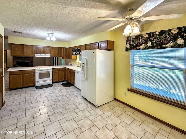 kitchen featuring a sink, visible vents, light countertops, ventilation hood, and white appliances