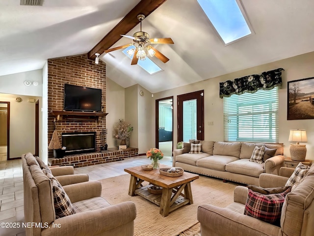 living room with lofted ceiling with skylight, a ceiling fan, and a brick fireplace