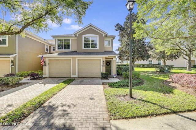 11929 Surfbird Cir Unit 12F, Jacksonville, FL 32256 - traditional-style home featuring a front yard, stucco siding, decorative driveway, and an attached garage