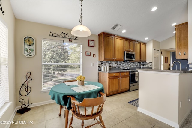 11929 Surfbird Cir Unit 12F, Jacksonville, FL 32256 - kitchen featuring tasteful backsplash, light tile patterned floors, brown cabinetry, recessed lighting, and stainless steel appliances