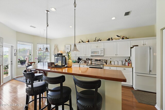 708 El Vergel Ln, Saint Augustine, FL 32080 - kitchen with butcher block countertops, dark wood-style flooring, white appliances, white cabinetry, and visible vents