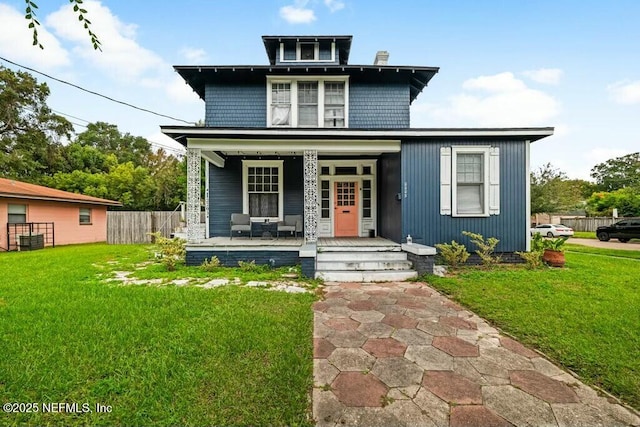 traditional style home with covered porch, fence, and a front lawn
