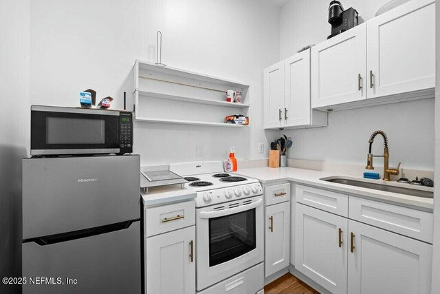 kitchen with light countertops, open shelves, white cabinets, appliances with stainless steel finishes, and a sink