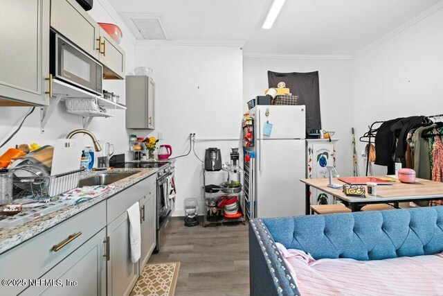 kitchen with black microwave, freestanding refrigerator, crown molding, electric range oven, and wood finished floors