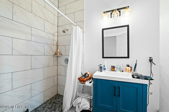 bathroom with tiled shower and vanity