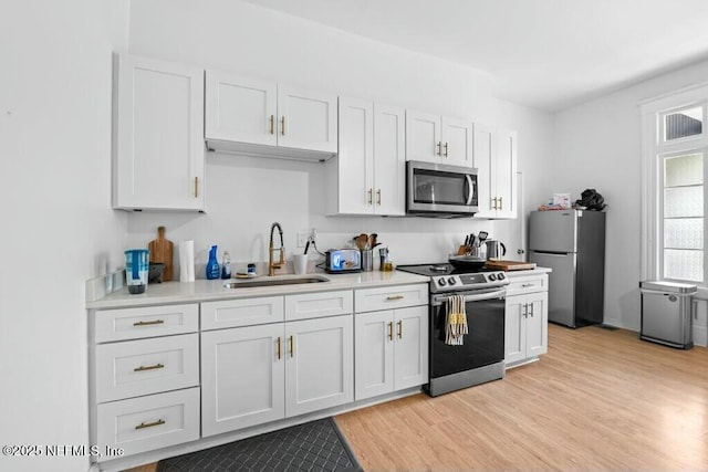 kitchen with light wood-type flooring, light countertops, a sink, and appliances with stainless steel finishes