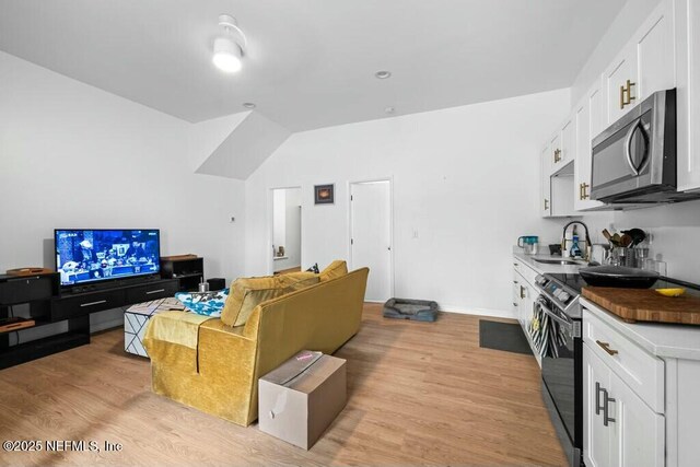 living room featuring light wood-type flooring, baseboards, and lofted ceiling