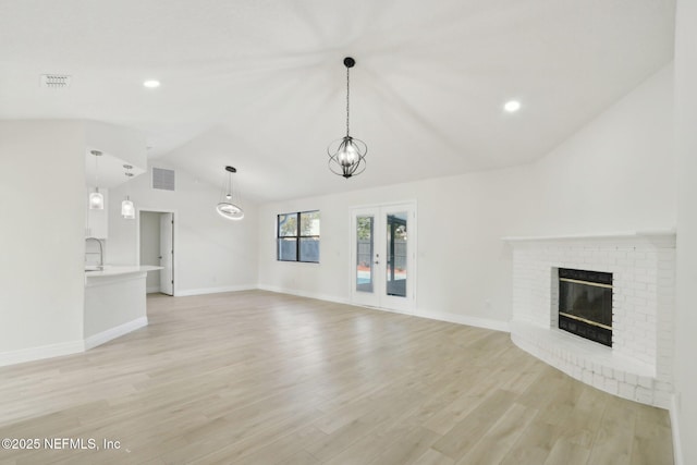 unfurnished living room with visible vents, a brick fireplace, light wood-style flooring, baseboards, and vaulted ceiling