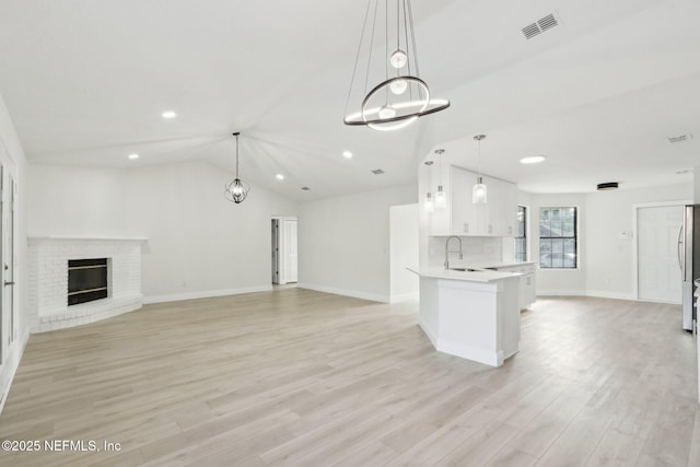 unfurnished living room featuring visible vents, a sink, baseboards, light wood finished floors, and recessed lighting