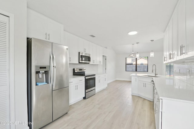 kitchen featuring backsplash, appliances with stainless steel finishes, a sink, light countertops, and white cabinetry