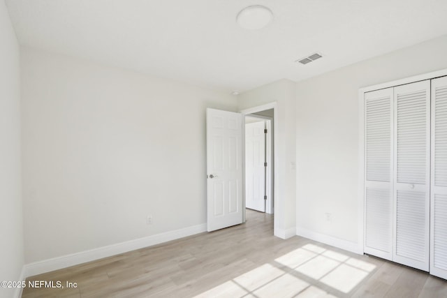 unfurnished bedroom with visible vents, baseboards, a closet, and light wood-type flooring
