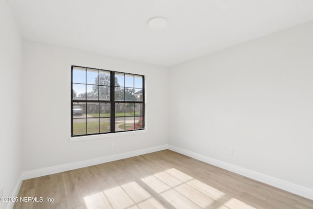 empty room featuring baseboards and light wood finished floors