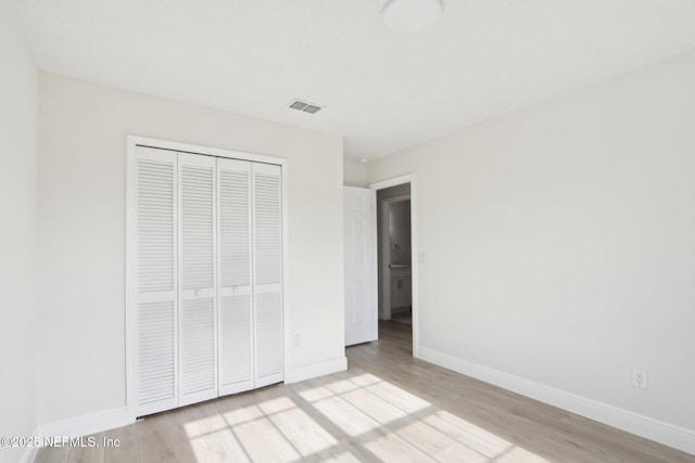 unfurnished bedroom featuring visible vents, baseboards, a closet, and light wood-type flooring