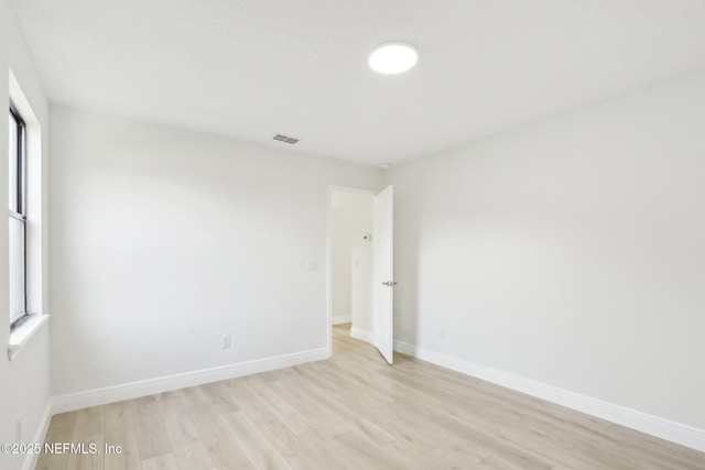 empty room with visible vents, light wood-style floors, and baseboards