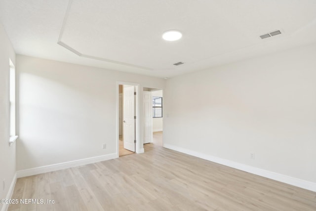 spare room with baseboards, light wood finished floors, and visible vents