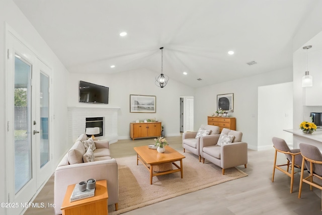 living area featuring visible vents, a fireplace, light wood-type flooring, baseboards, and lofted ceiling